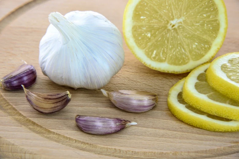 Cesnek s cibulí a citrony na dřevěném prknu