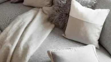 Šedé pohovka s polštáři v odstínech taupe a béžové.