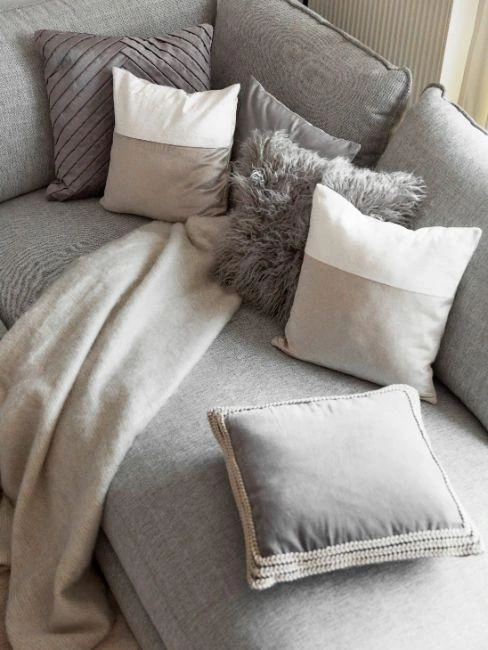 Šedé pohovka s polštáři v odstínech taupe a béžové.