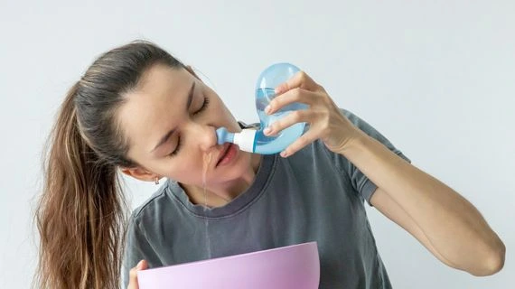 Žena používá nosní zavlažování pro nachlazení.