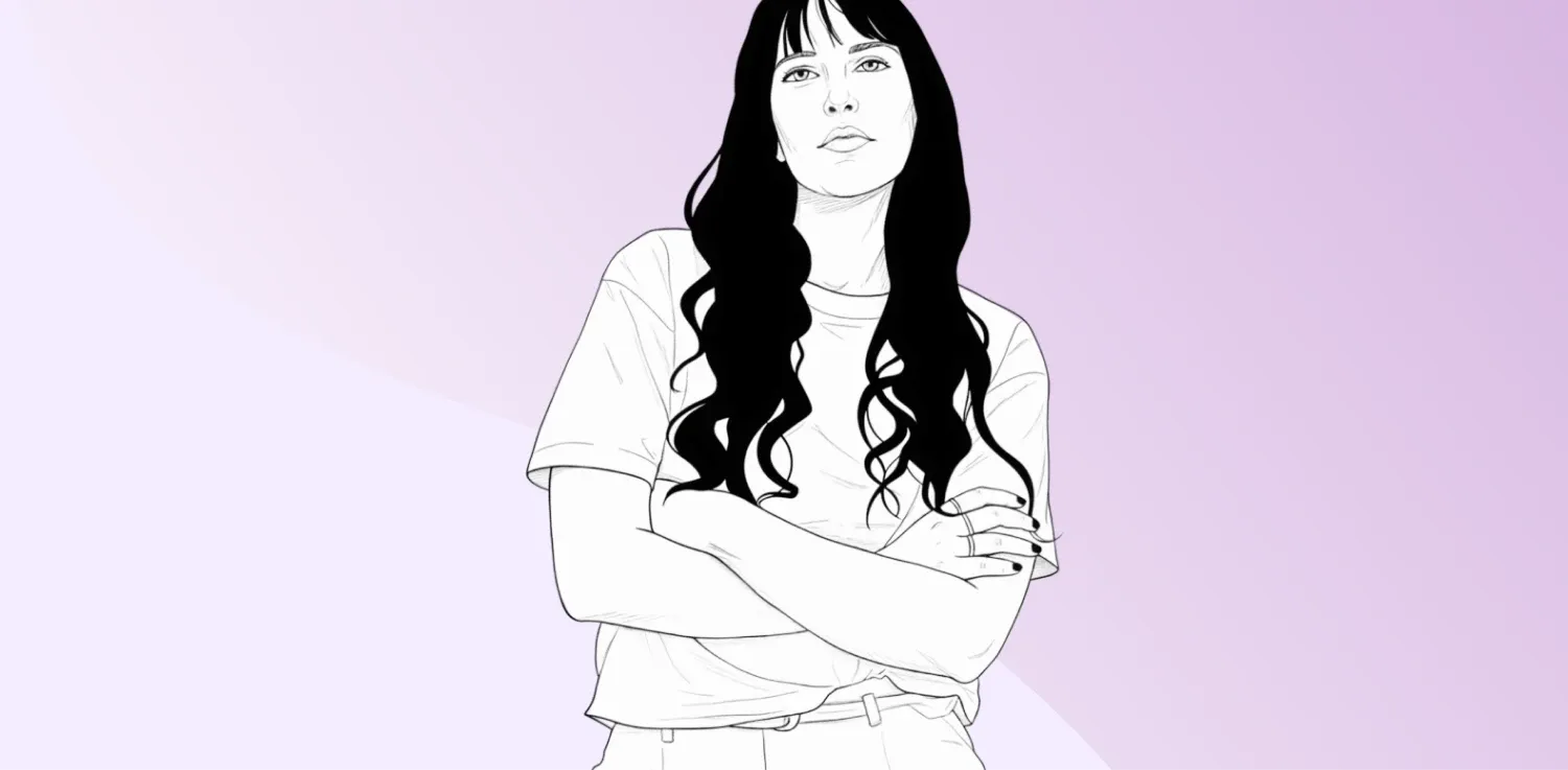 Žena s dlouhými vlasy v bílé tričku se zkříženýma rukama.