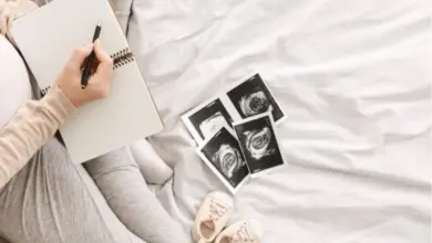 Těhotná žena píše do sešitu vedle ultrazvukových snímků.